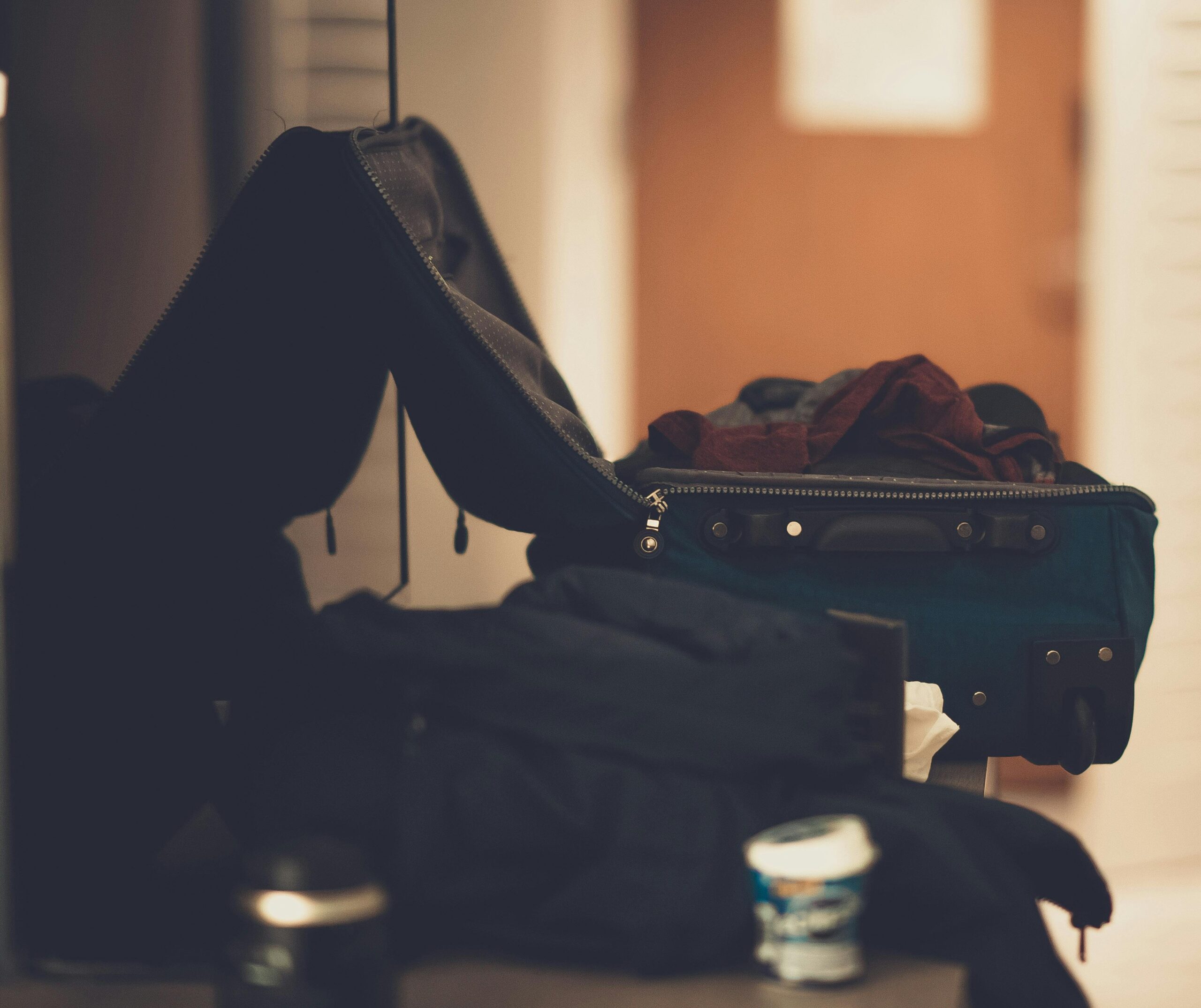 An overstuffed suitcase spilling clothes everywhere