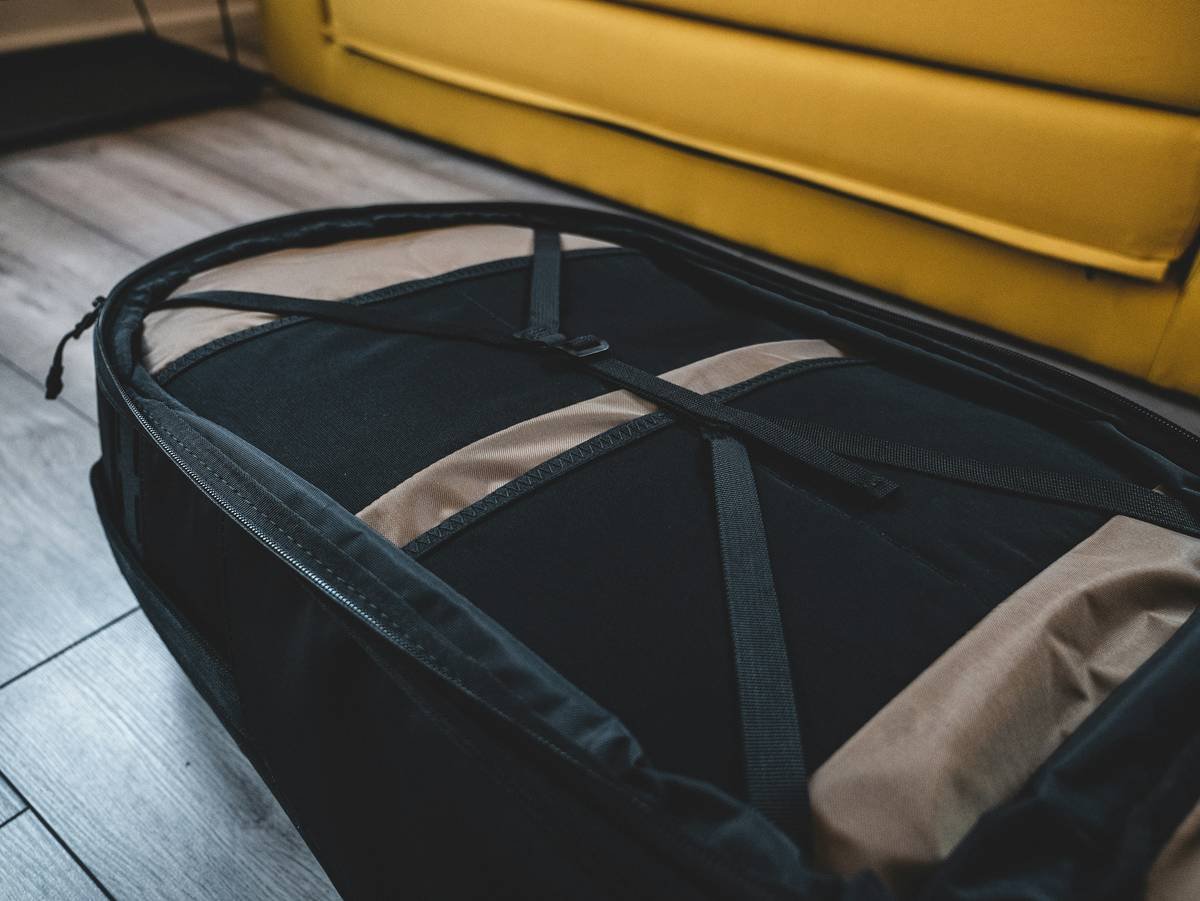 A sleek black flex pack overnight bag sitting next to airplane tickets and sunglasses