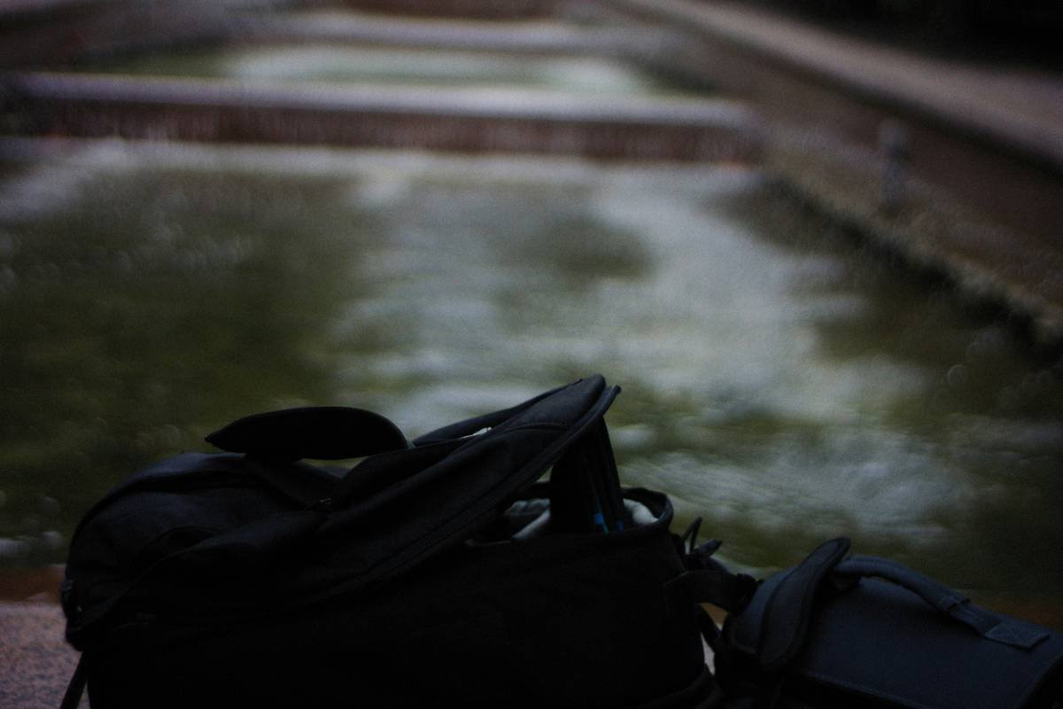 A woman struggling to close her overpacked suitcase.
