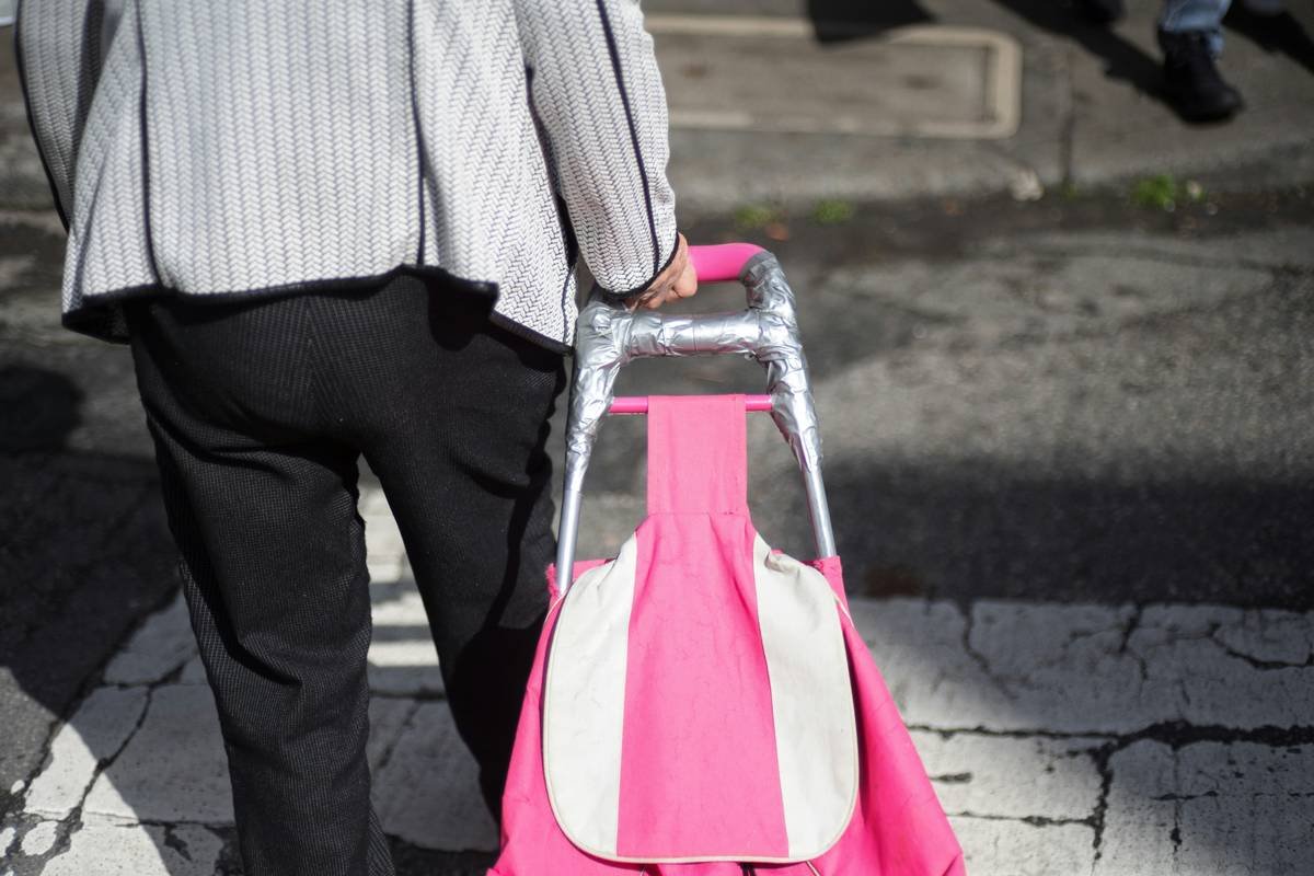 Woman smiling next to fully expanded space saving trolley bag filled with colorful scarves