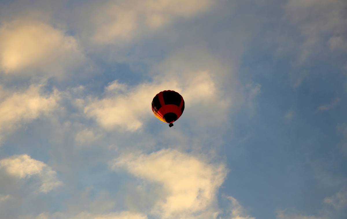 A sleek black expandable suitcase next to a pile of clothes, showcasing its extra capacity.