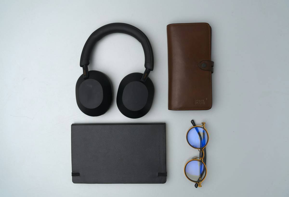 A minimalist flat lay of my everyday carry items— wallet, notebook, spectacles, and headphones—carefully arranged on a white surface. A visual reflection of simplicity and order in daily life.