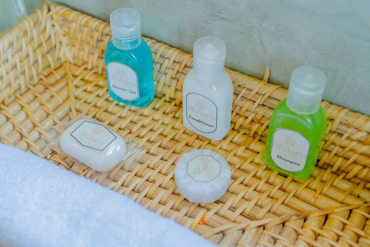 A neatly arranged wicker tray with hotel toiletries including shampoo, conditioner, shower gel, and soaps. A clean, welcoming detail often found in quality hospitality setups.