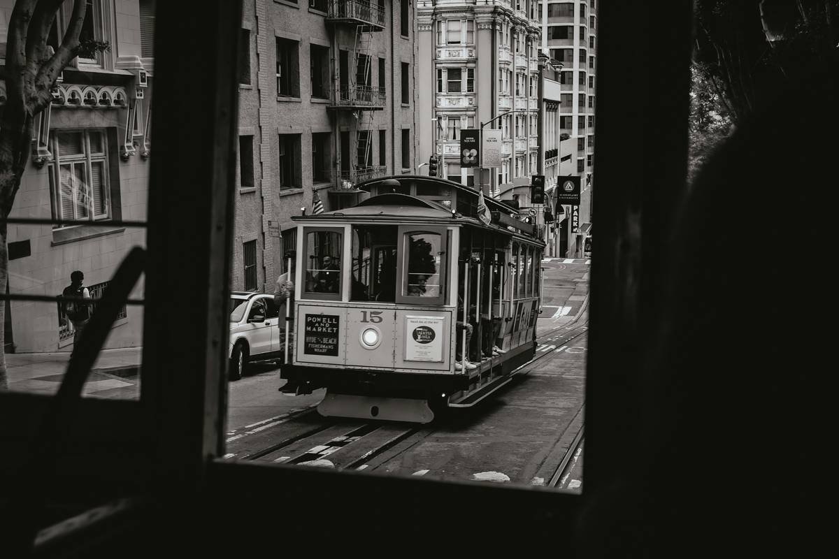 A vintage cable car travels down a city street.