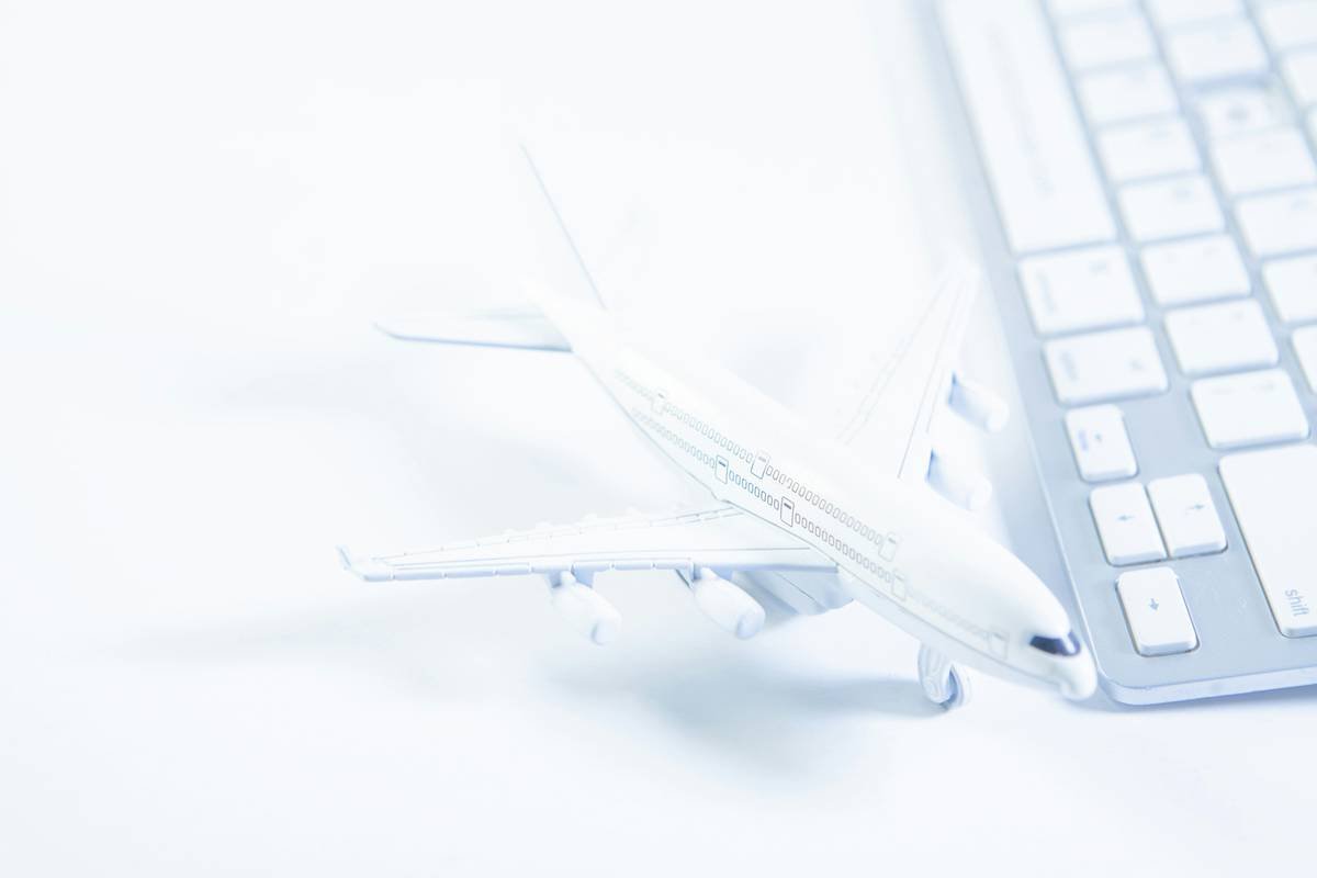 airplane model and keyboard on white background, travel and business concept